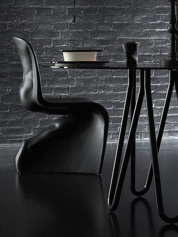 Schwarzer Him Stuhl von Casamania Horm neben einem Esstisch mit Geschirr. Designermöbel.