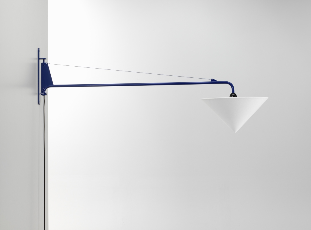 Vitra Potence Wandleuchte mit blauem Arm und konischem, weißem Lampenschirm vor einer weißen Wand.