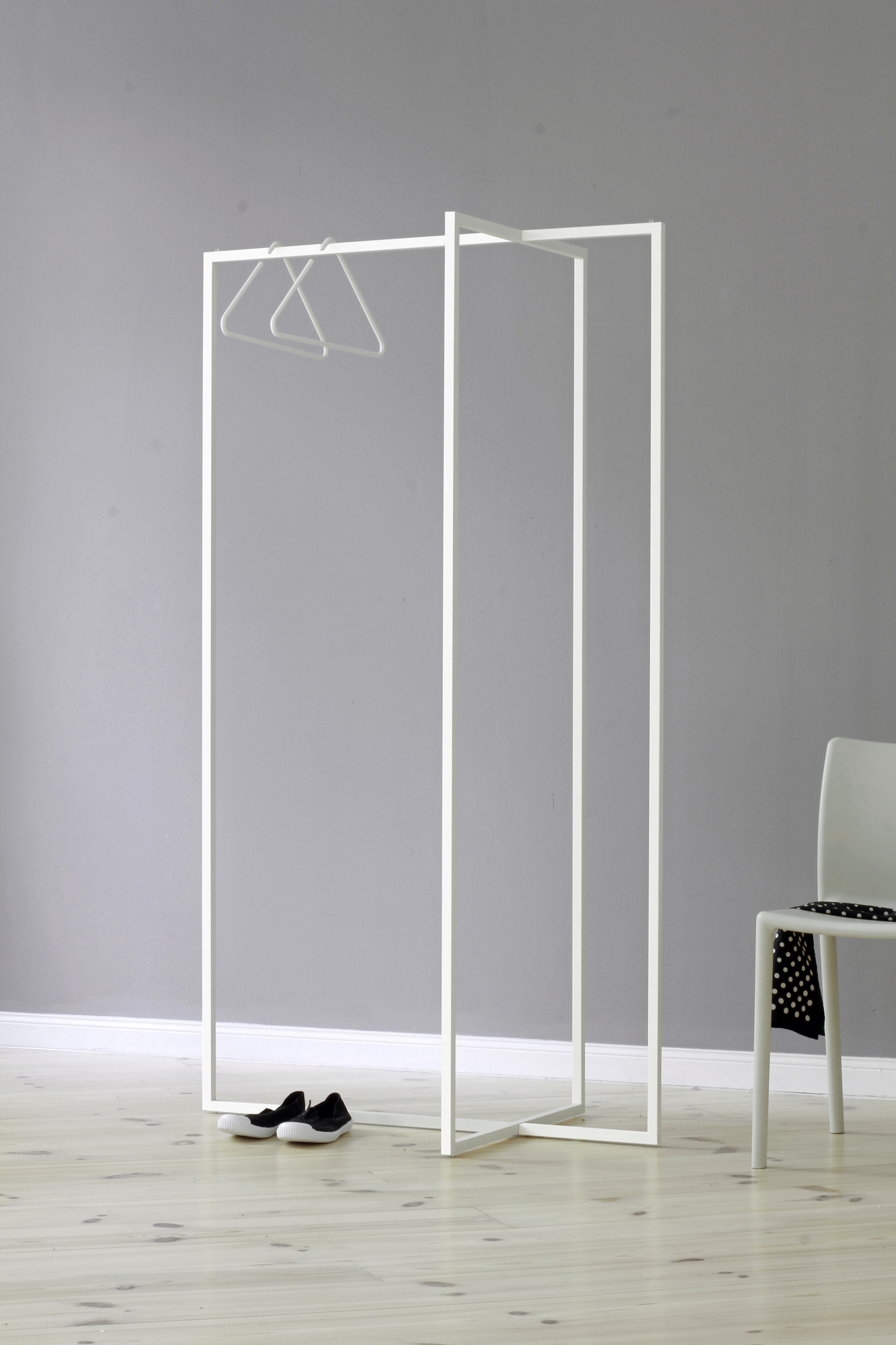 Roomsafari Modular Frames L Garderobe in Weiß mit Kleiderbügeln, Schuhen und Stuhl. Moderne Garderobenlösung.