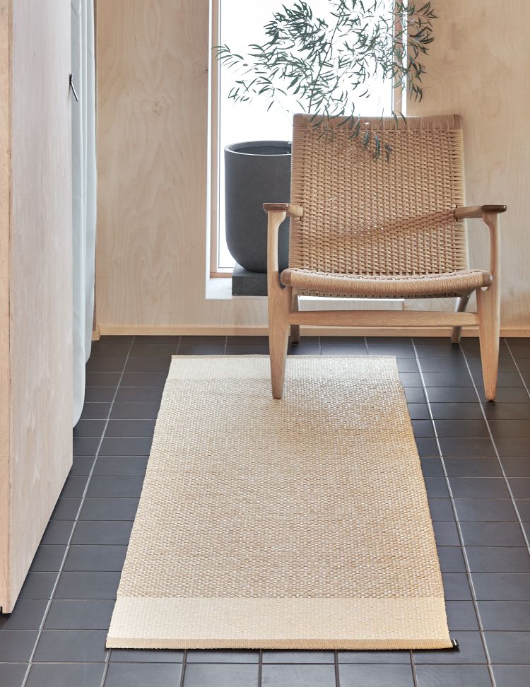 Pappelina Teppich Edit in Beige, Größe 230x320 cm, im modernen Interieur mit Stuhl auf Fliesenboden.