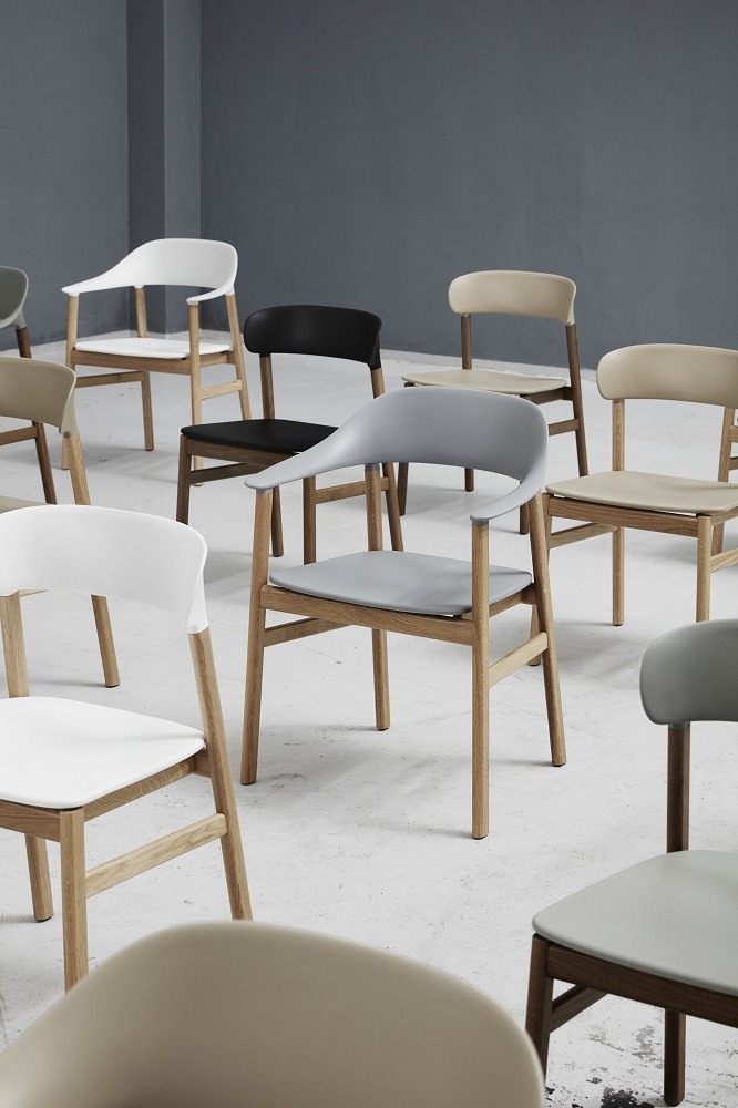 Nahaufnahme von mehreren Herit Chair Stühlen von Normann Copenhagen in verschiedenen Farben und Holzrahmen.