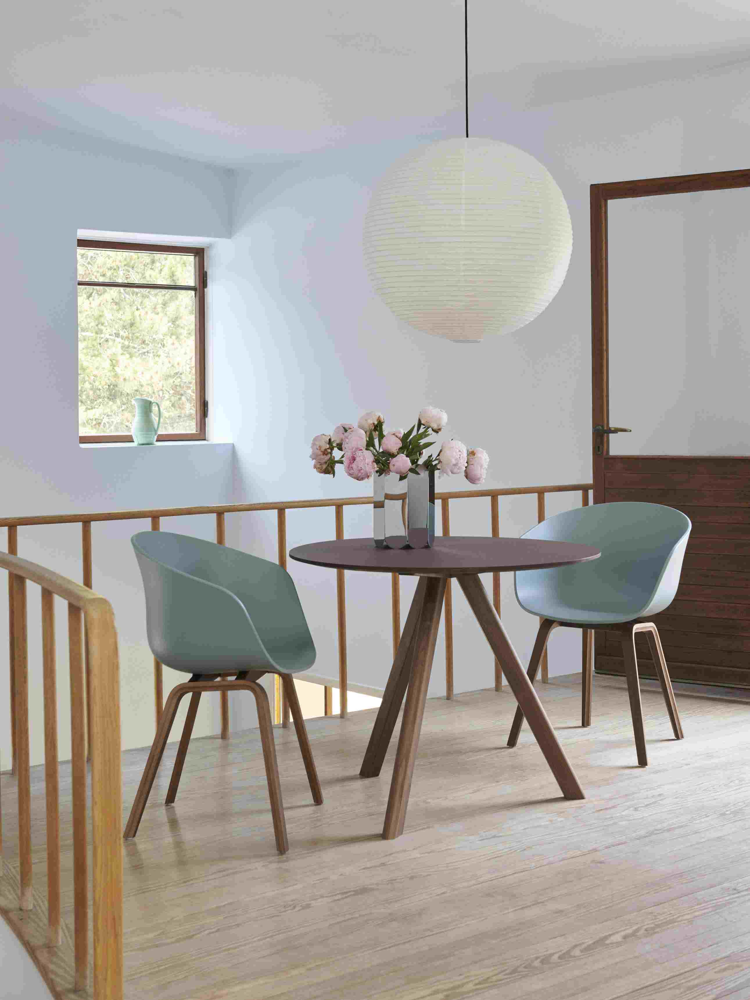 Esszimmer mit Hay Stühlen, Holztisch und Arcs Vase L Mirror mit rosa Pfingstrosen.