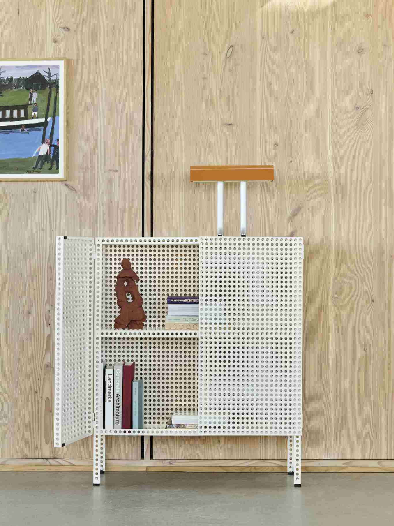 Weißes Perforated Cabinet Sideboard von Hay mit perforierter Metallstruktur, teilweise geöffnet, mit Büchern und Dekoration.