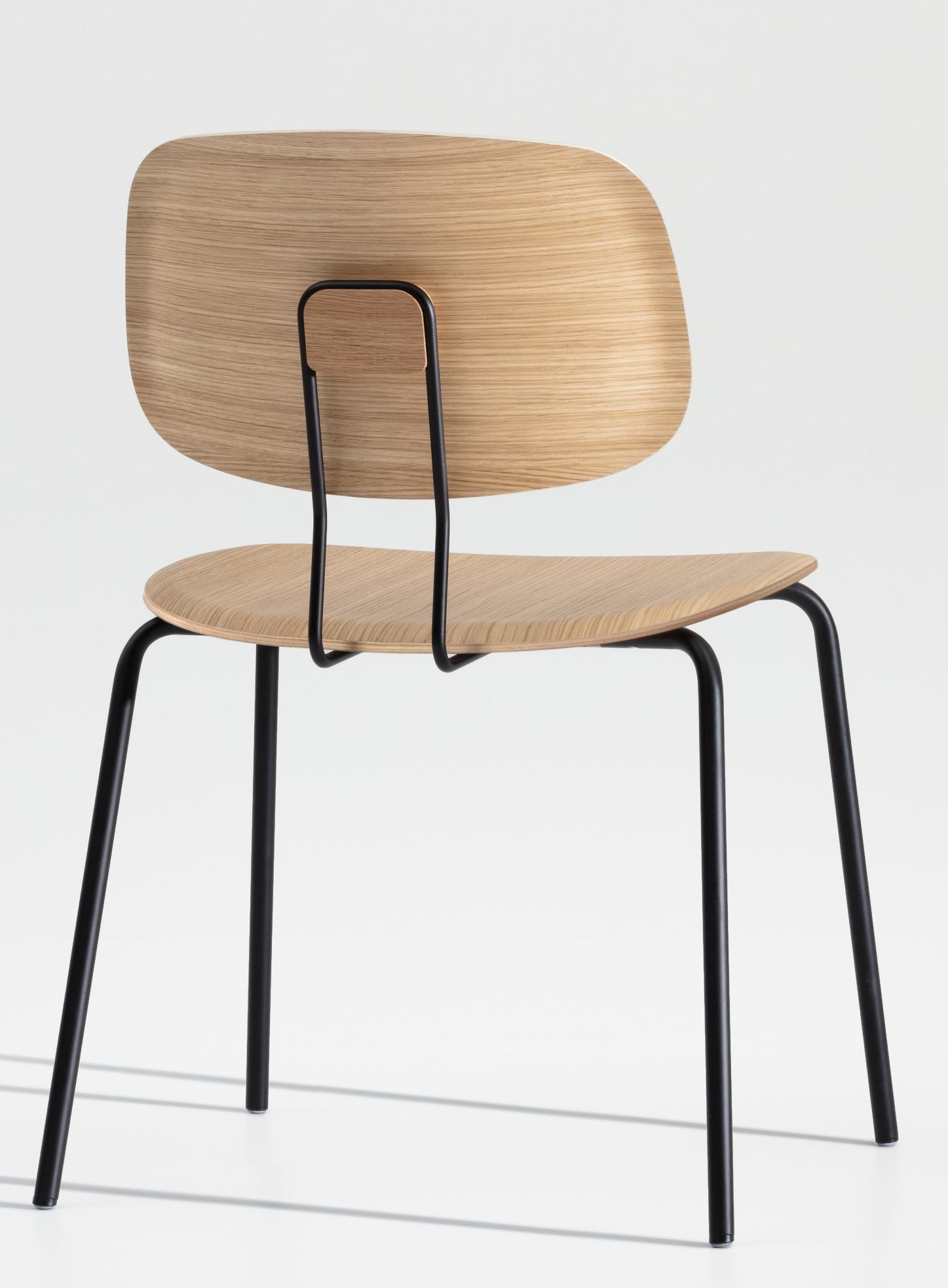 Rückansicht des Okito Ply Dining Chair Stuhls mit hellem Holz und schwarzem Metallgestell.