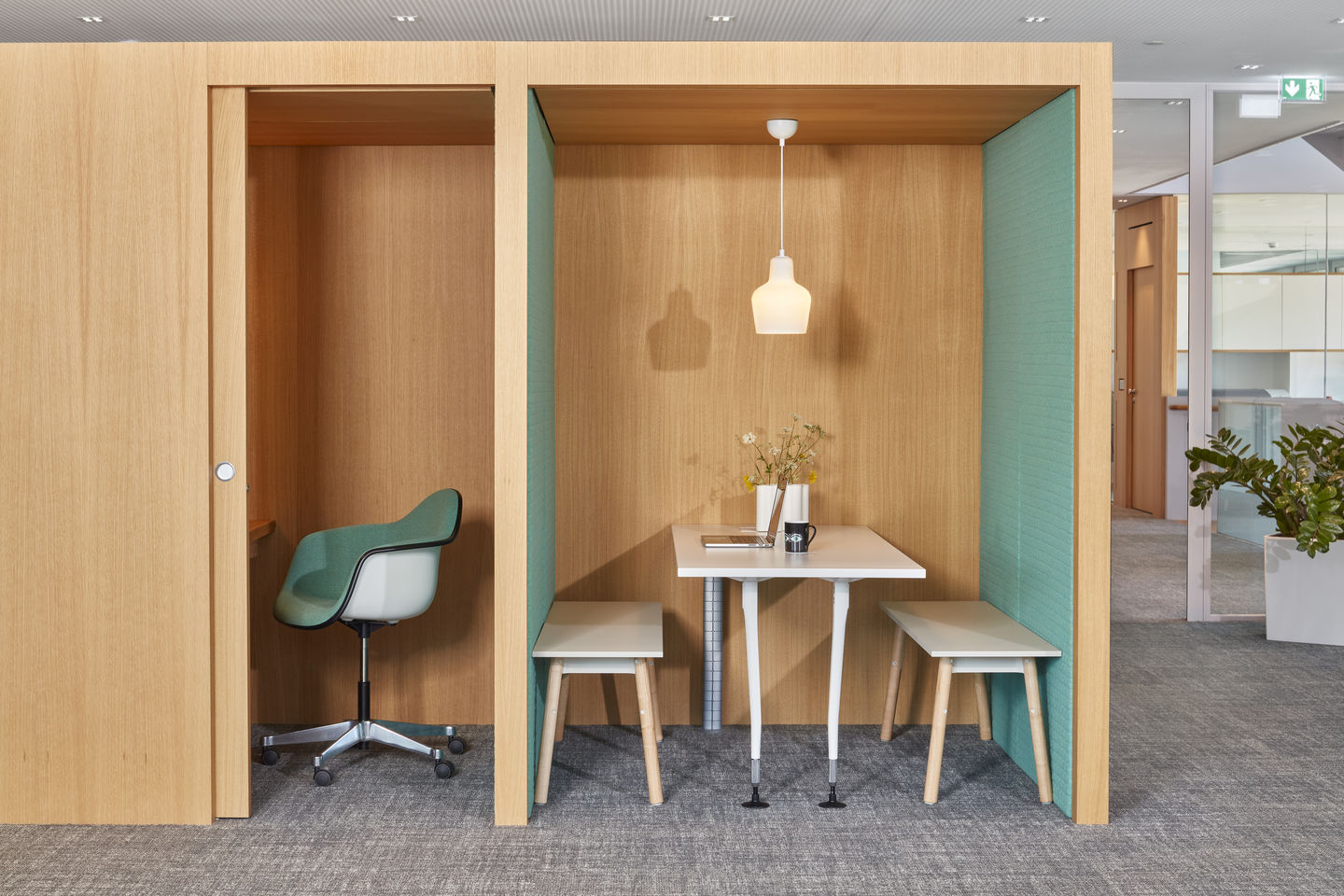 Büro-Szene mit Eames Plastic Arm Chair in Grün, Schreibtisch und Sitzbank in Holzkabine.