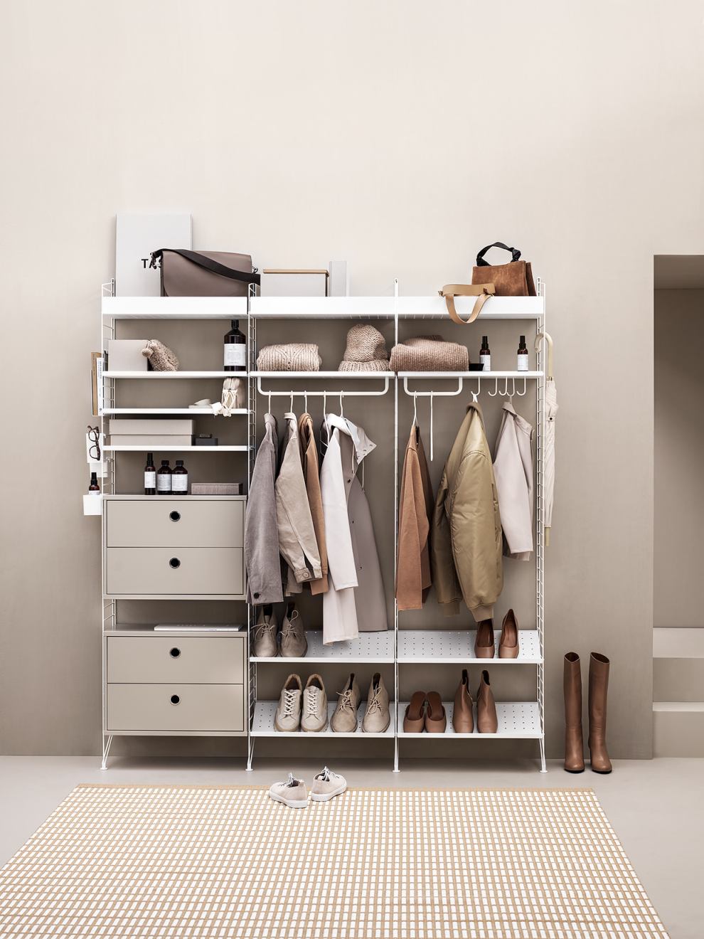 Helles Flurregal-System von String Furniture mit Kleidung, Schuhen und Accessoires für eine stilvolle Flurgestaltung.