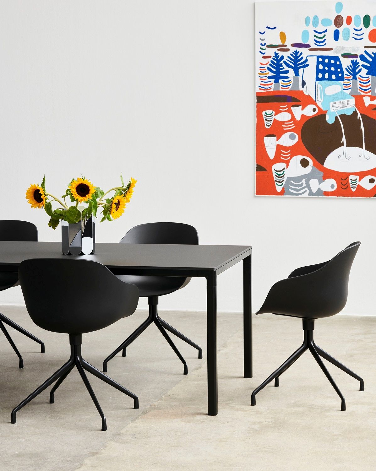 Schwarzer Esstisch mit vier schwarzen Hay AAC 220 Stühlen und abstrakter Kunst an der Wand.