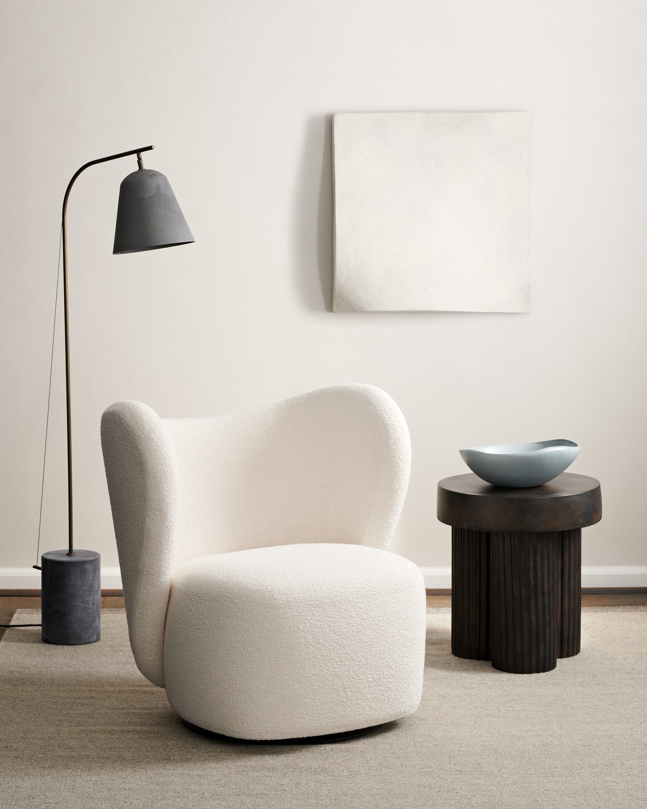 Norr11 Gear Tall Side Table aus dunklem Holz neben Sessel und Stehlampe in minimalistischem Interieur.
