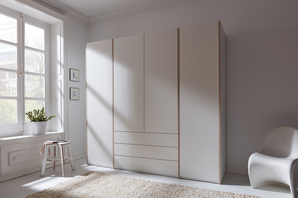 Moderner, weißer Kleiderschrank mit Schubladen und Türen im Schlafzimmer, ideal für die Aufbewahrung von Kleidung.