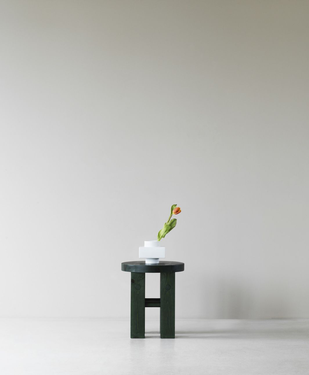 Fyr Stool Hocker von Normann Copenhagen, dunkelgrüner Holzhocker mit Tulpe in weißer Vase.