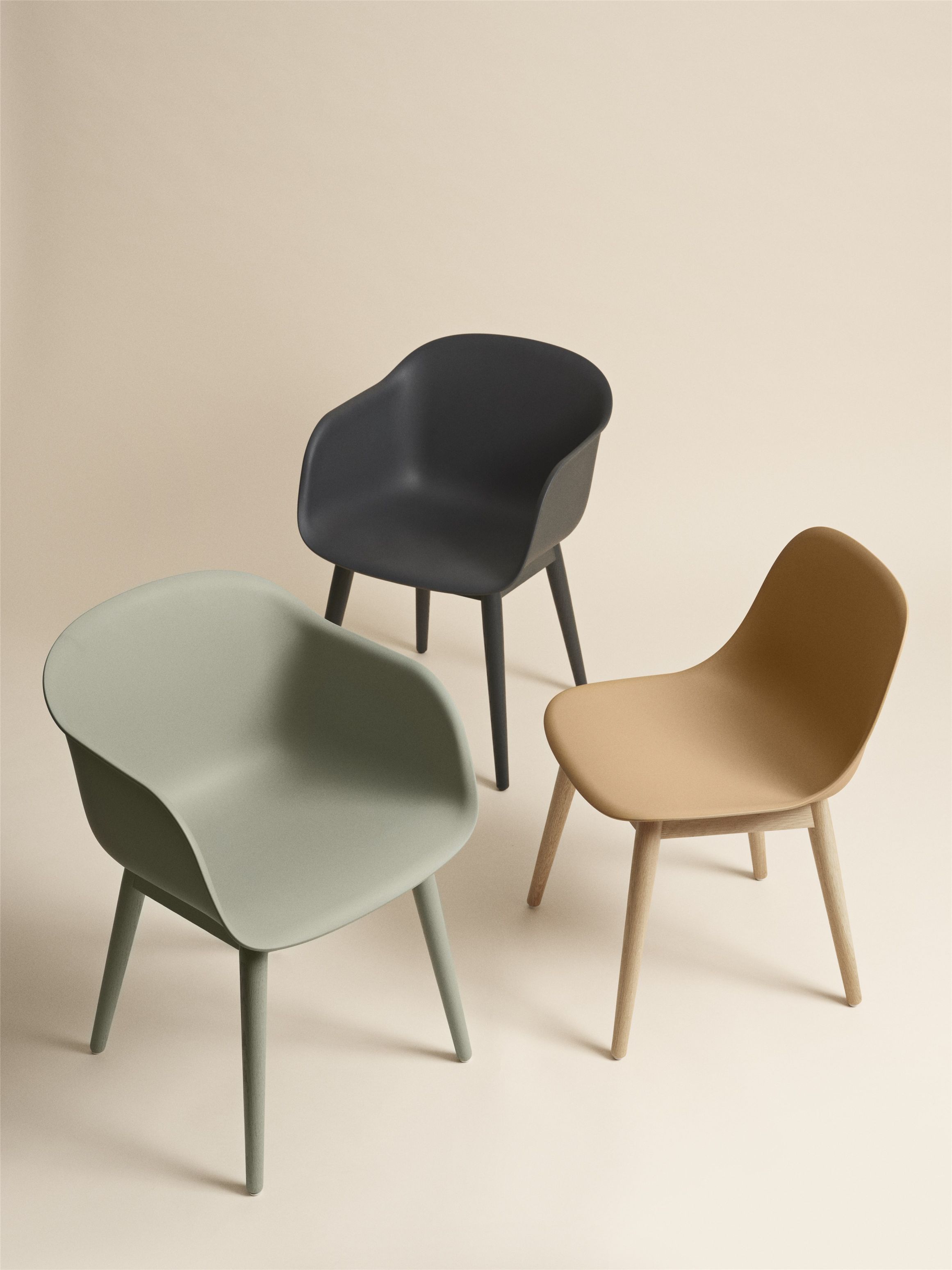 Drei Muuto Fiber Armchair Stühle mit Holzbeinen in Grün, Schwarz und Beige. Designermöbel für Wohnzimmer.