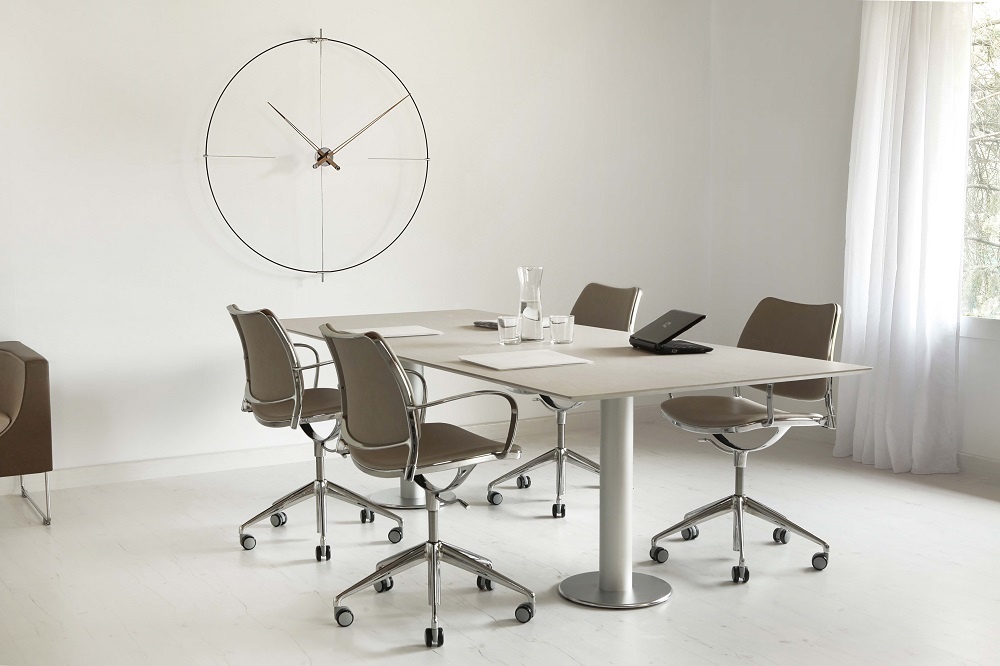 Minimalistische Bilbao Nomon Wanduhr in Schwarz-Schwarz über einem Konferenztisch in einem hellen Büro.