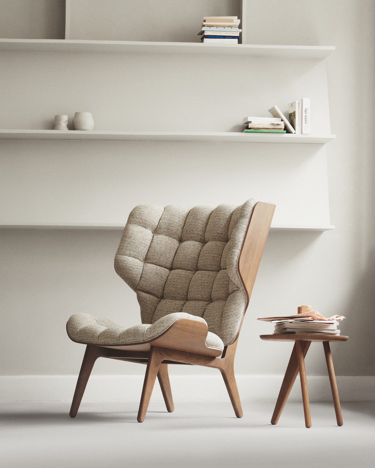 Norr11 Fin Side Table Beistelltisch aus Holz neben einem Sessel mit Stoffbezug und Bücher auf dem Tisch.