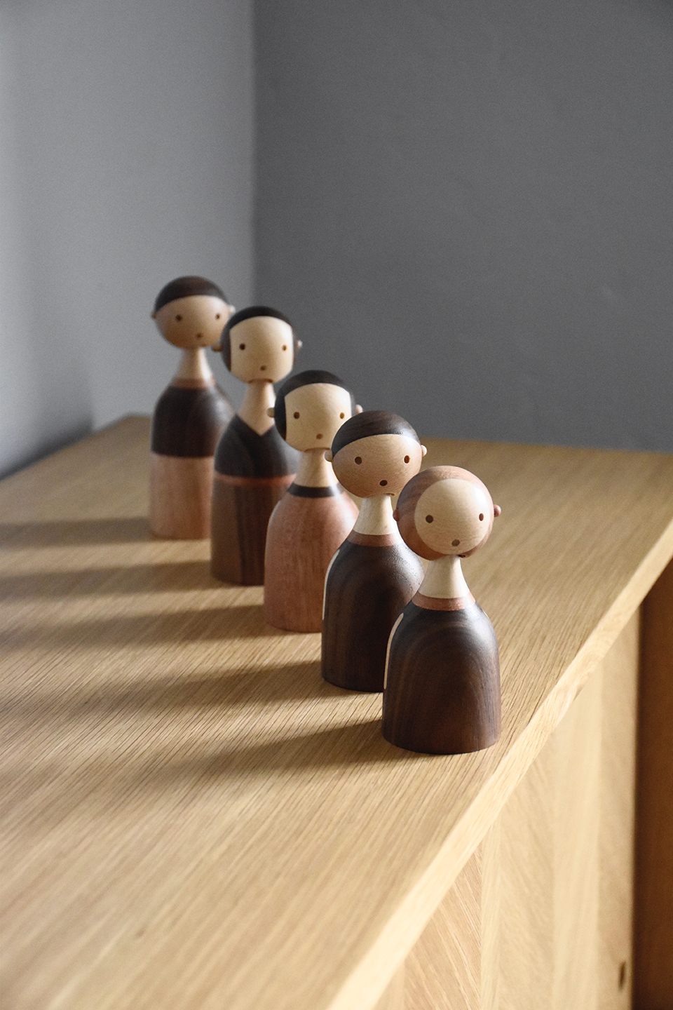 Fünf Kin Holzfiguren von Architectmade, handgefertigte Deko-Objekte aus Holz, auf einem Tisch arrangiert.