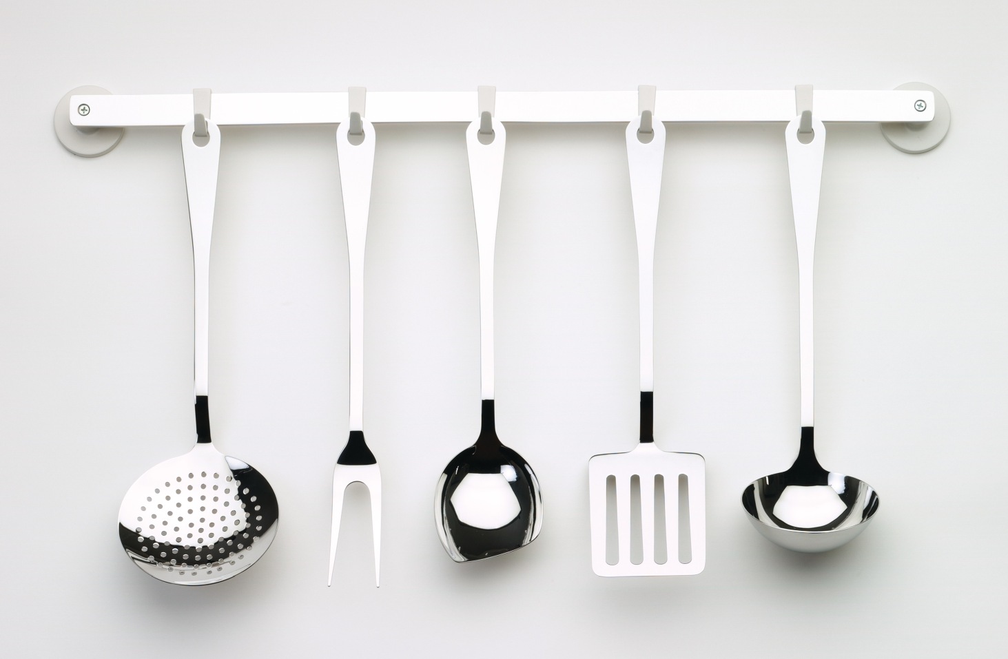 Alessi Küchenset AJM19S5 L: Fünf Küchenhelfer aus Edelstahl hängen an einer weißen Küchenleiste.
