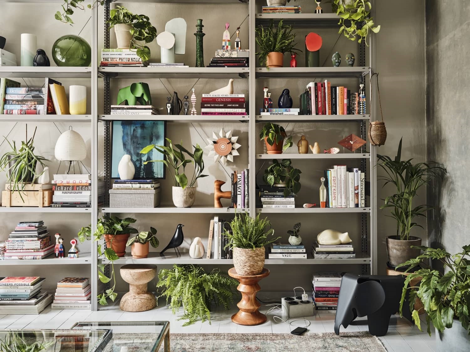 Graues Regal mit Deko-Objekten, Pflanzen und Büchern. Wohnaccessoires für stilvolles Wohnen und dekorative Inneneinrichtung.