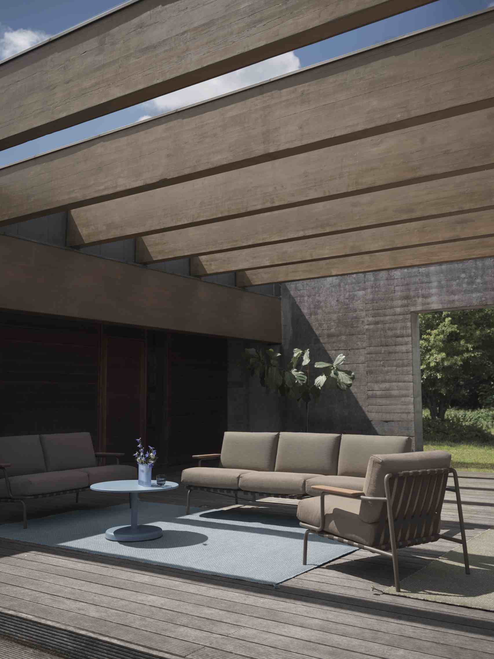 Muuto Ply Rug aus recyceltem Polyester, hellblauer Outdoor Teppich auf Holzterrasse mit Gartenmöbeln.