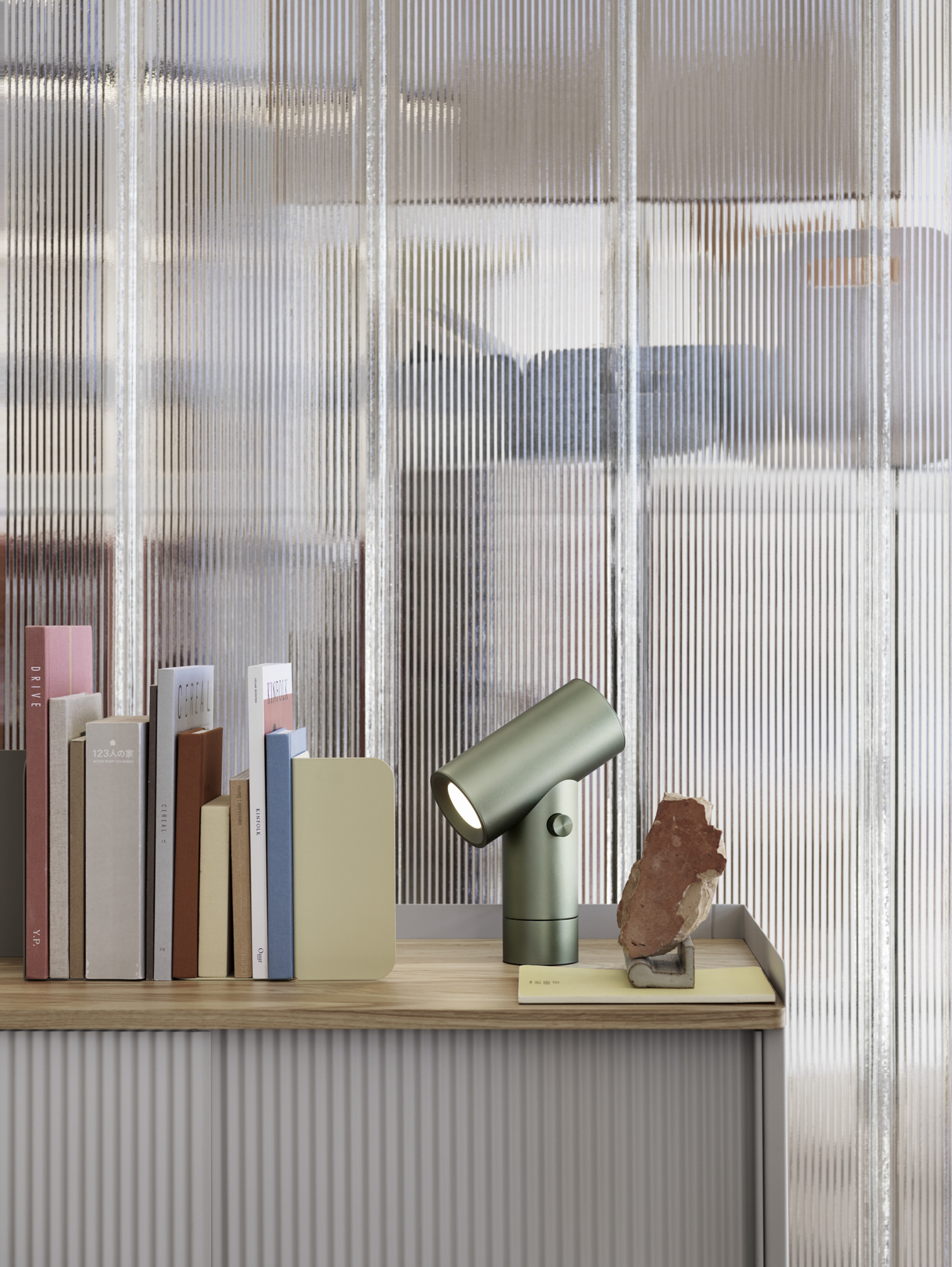Nahaufnahme der grünen Muuto Beam Tischleuchte aus Aluminium auf einem Regal mit Büchern.