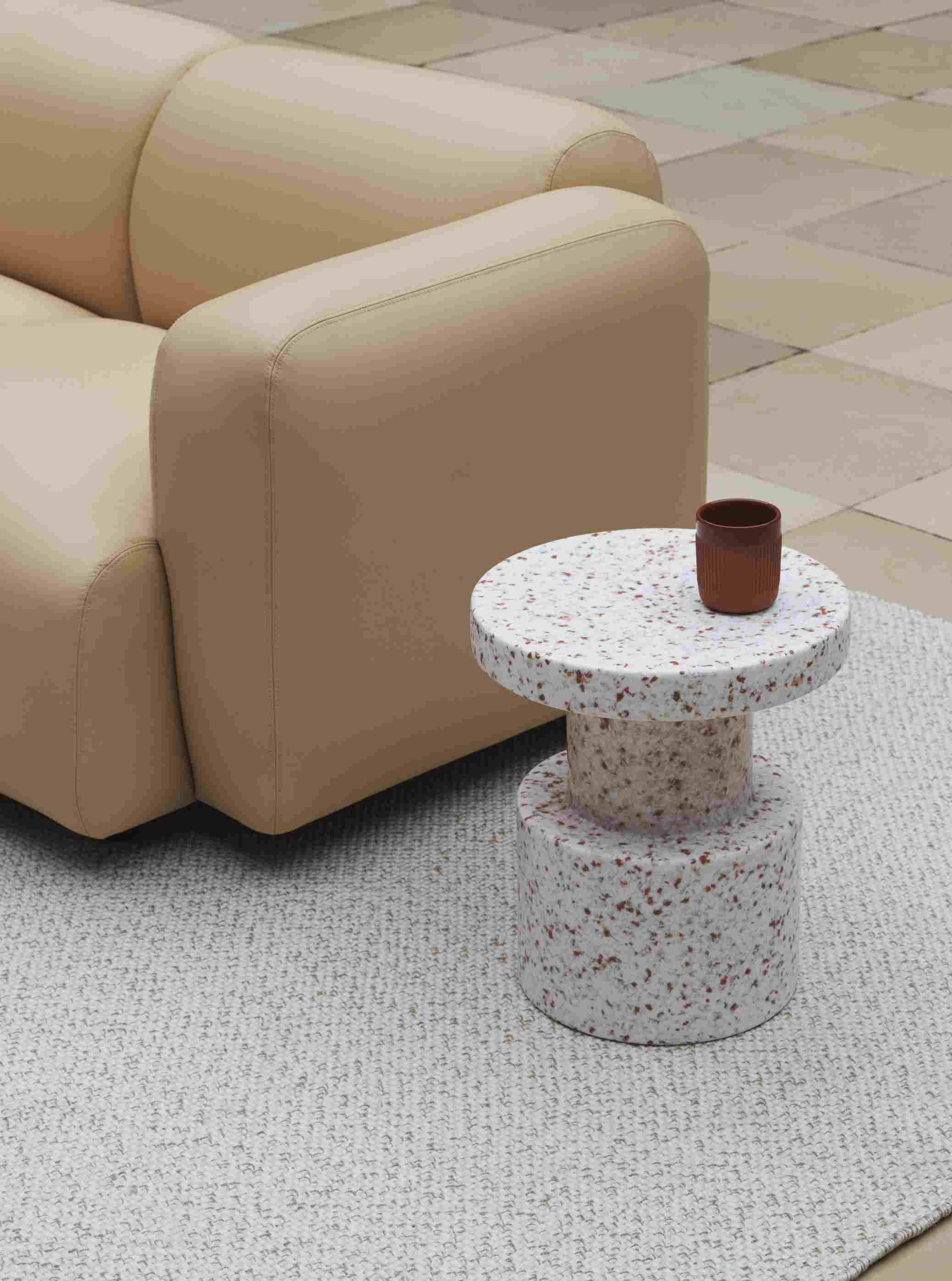 Normann Copenhagen Bit Stool Hocker mit Terrazzo-Muster neben beigem Sofa und brauner Tasse.