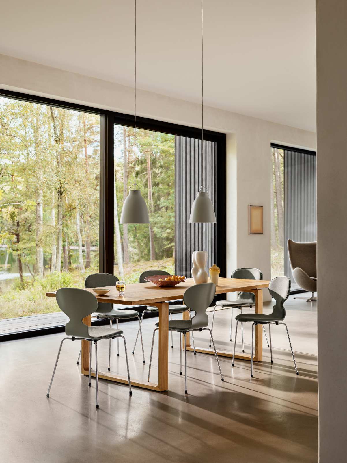 Esszimmer mit Esstisch, Stühlen und zwei grauen Caravaggio Pendelleuchten von Fritz Hansen.