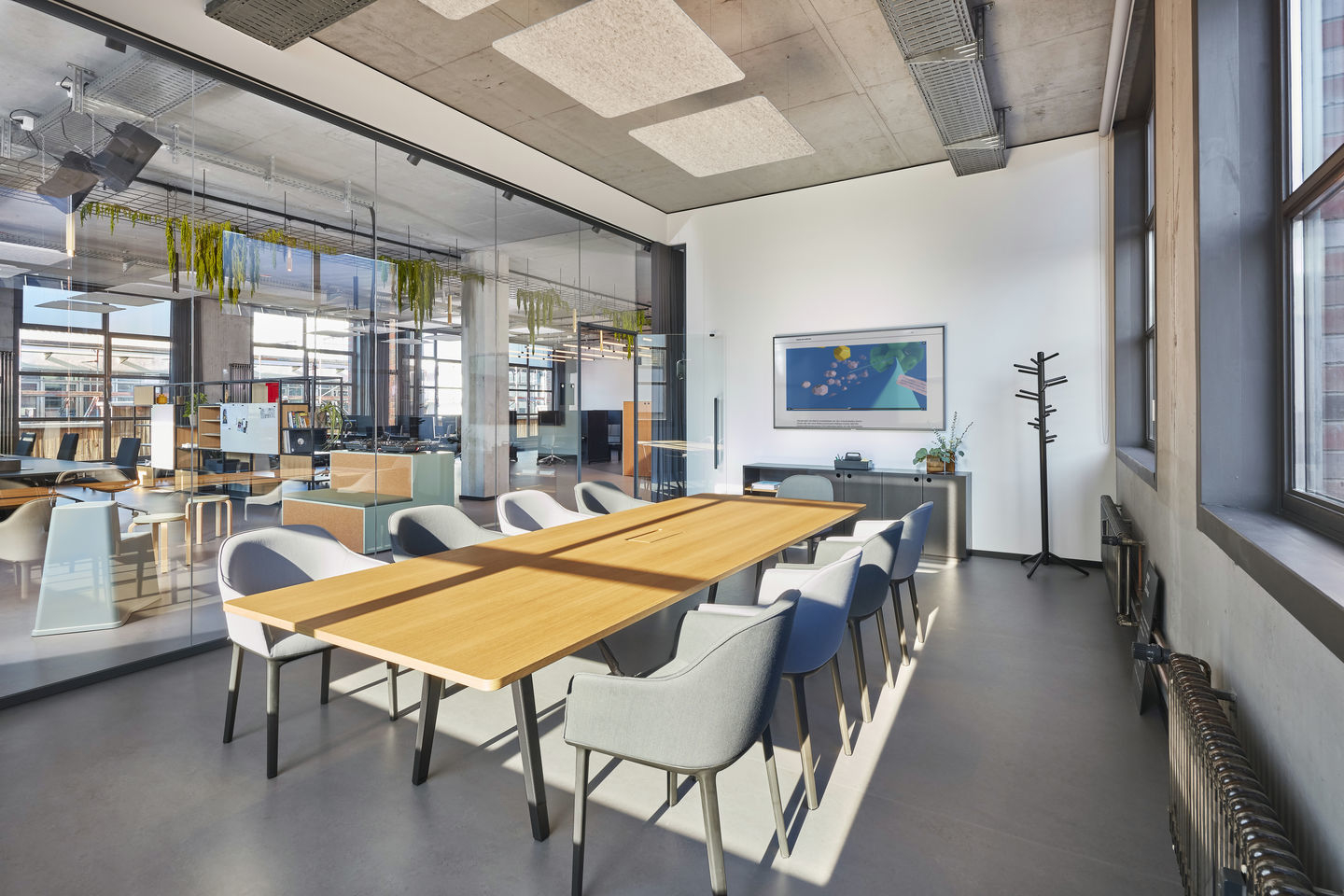 Konferenzraum mit langem Holztisch und grauen Softshell Chairs von Vitra mit Vierbein-Gestell.