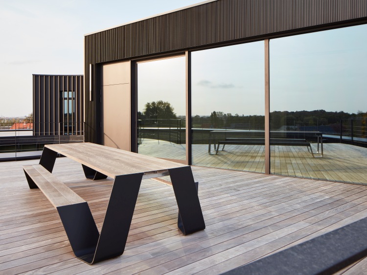 Hopper Picnic Bank von Extremis für den Außenbereich auf einer Holzterrasse mit moderner Architektur.
