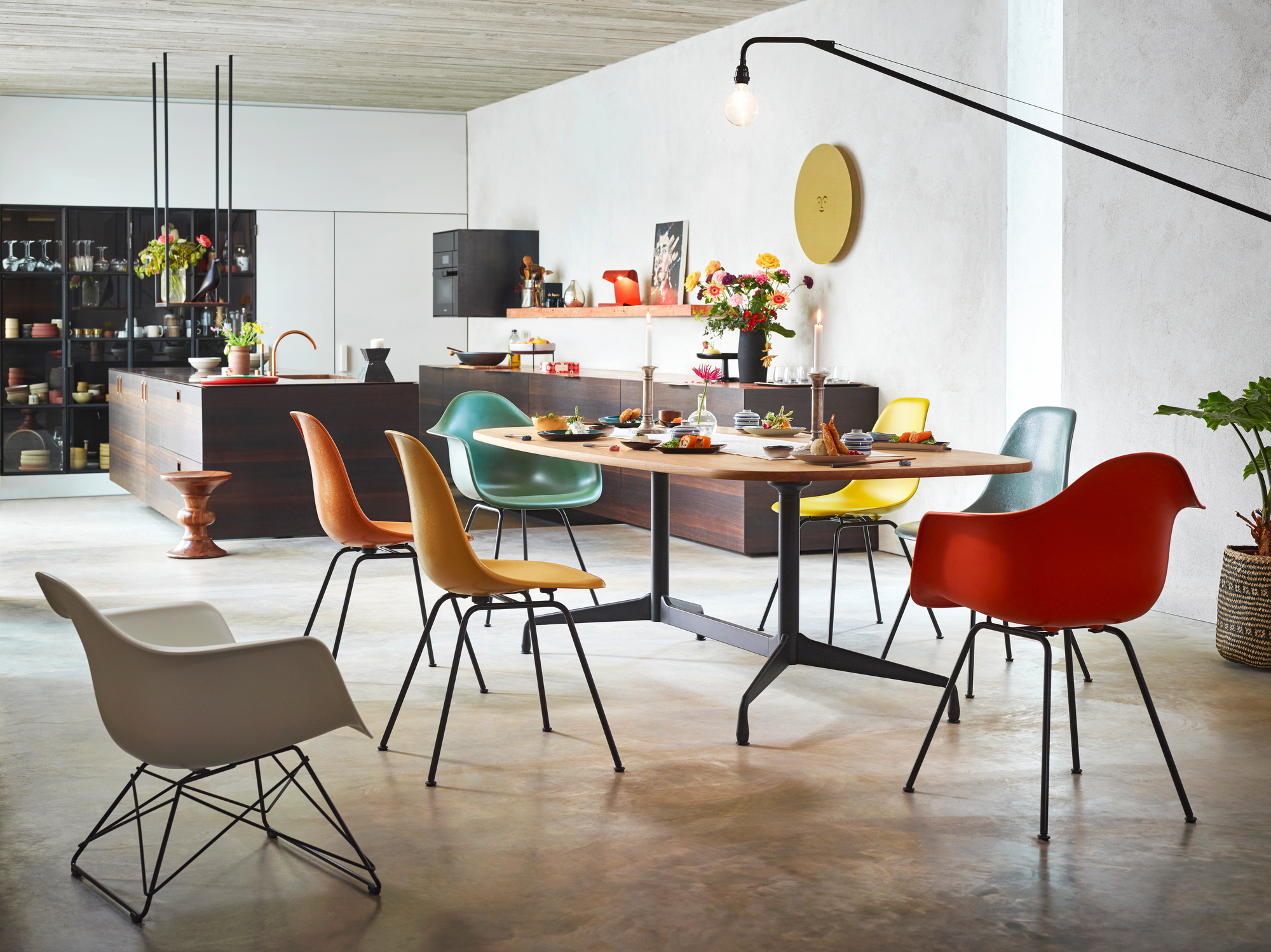 Esszimmer mit Eames Plastic Arm Chairs von Vitra in verschiedenen Farben und schwarzem Untergestell.