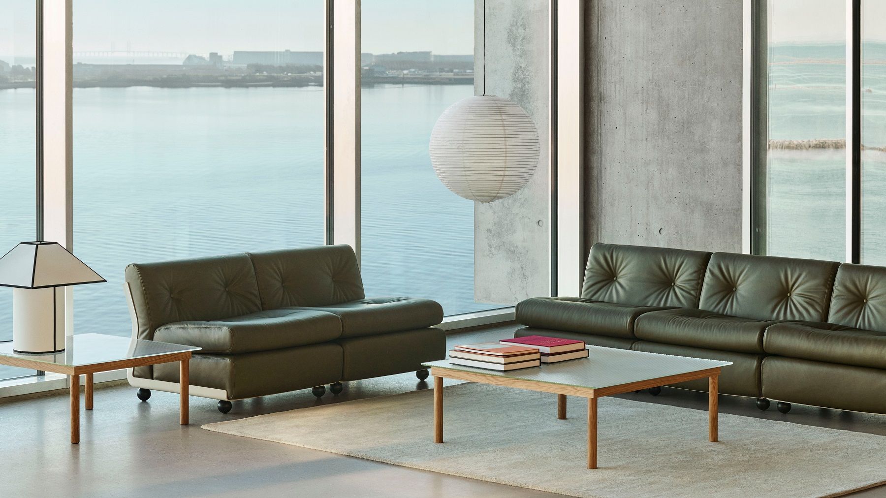 Helle moderne Inneneinrichtung mit Hay Ava Pyramid Tischleuchte, Sofas und Meerblick.