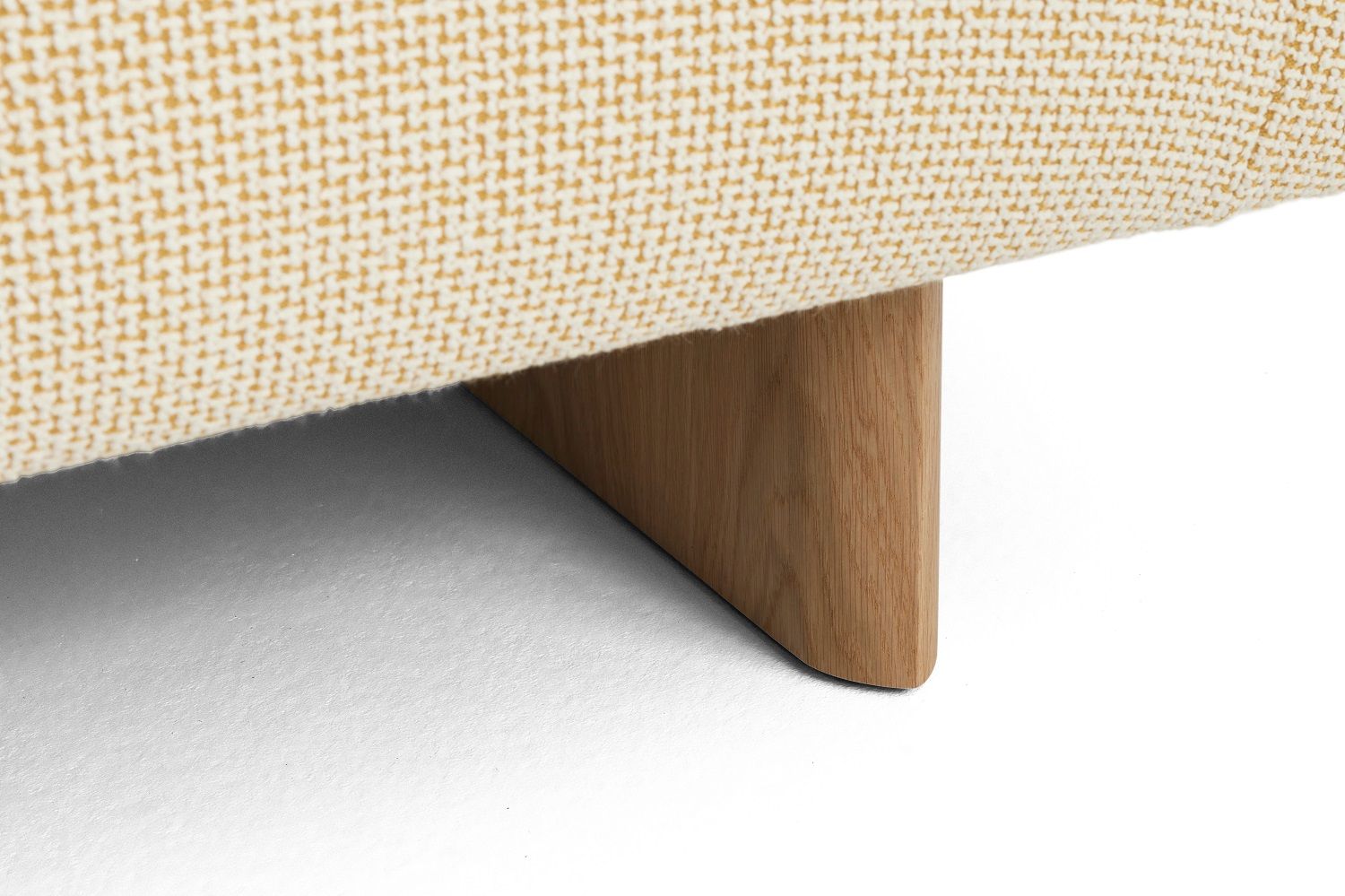Detailaufnahme vom Hay Quilton Sofa: Gelber Stoffbezug und helles Holzbein des modernen 2-Sitzer Sofas.