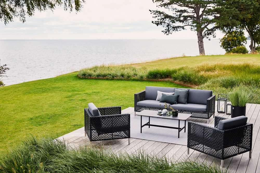 Cane-Line Connect Lounge Möbel: Sofa und Sessel mit grauen Kissen im Outdoor-Bereich.