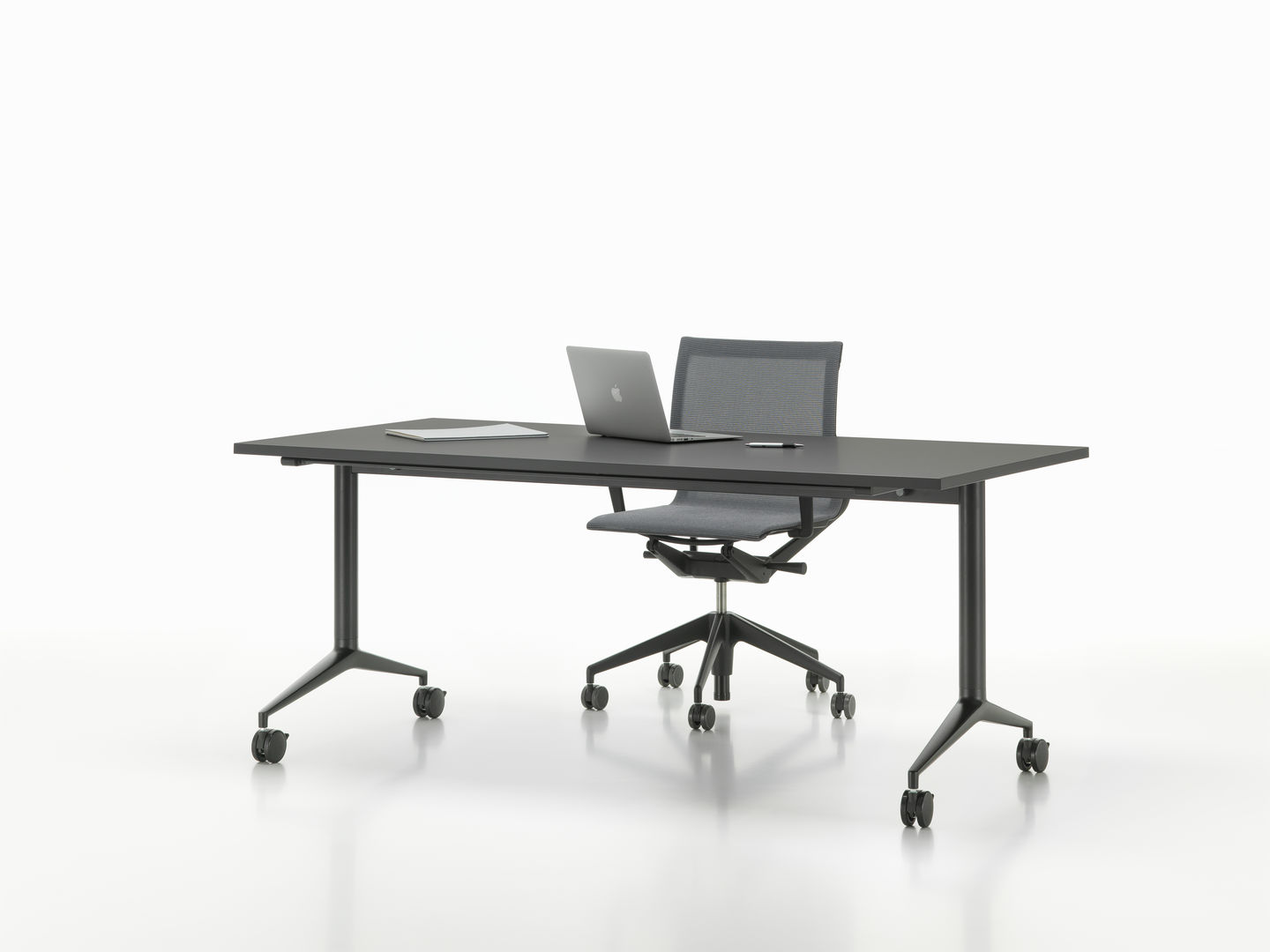Vitra MedaMorph Klapptisch in Schwarz mit Laptop und Bürostuhl auf Rollen vor weißem Hintergrund.