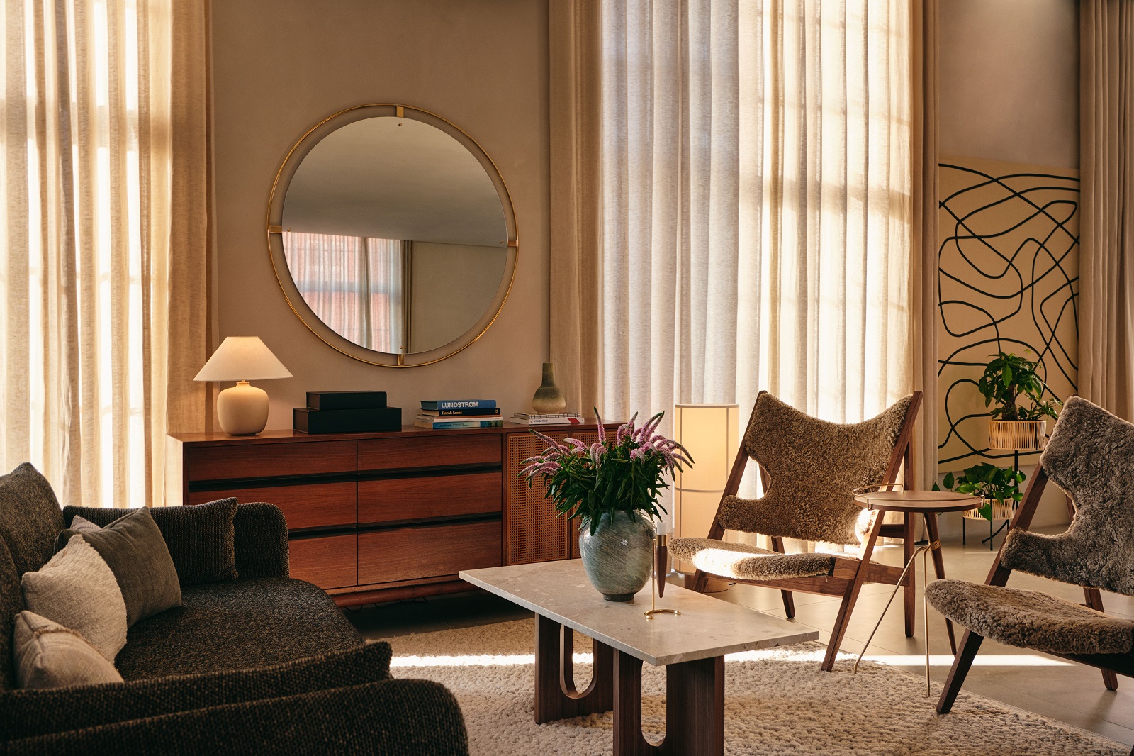 Wohnzimmer mit Audo Copenhagen Gravel Rug Teppich, Sofa, Sessel und Holztisch in warmen Farbtönen.