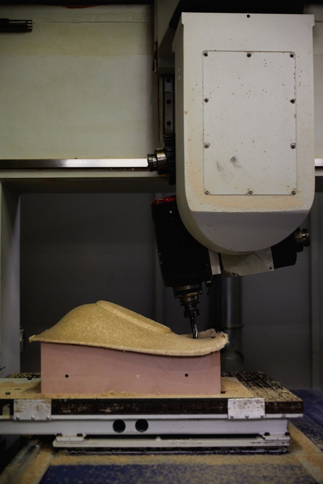 Fertigungsprozess eines Mat Armchair von Normann Copenhagen mit einer CNC-Fräse. Fokus auf die Formgebung der Sitzfläche.