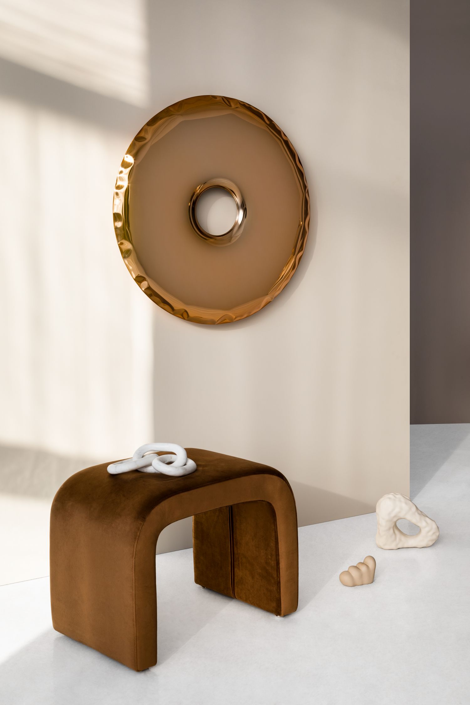 Rondo Spiegel Aurum Gold von Zieta, ein runder Wandspiegel mit goldenem Rahmen über einem braunen Samthocker.