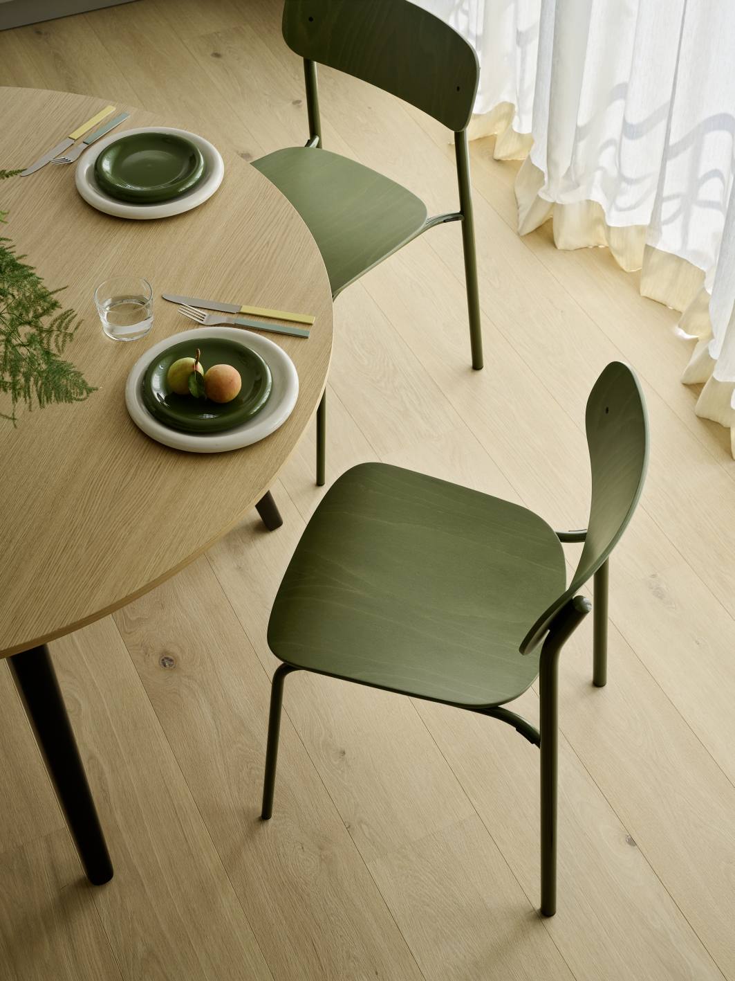 Nahaufnahme von zwei olivgrünen S 243 Stahlrohrstühlen von Thonet an einem Esstisch.