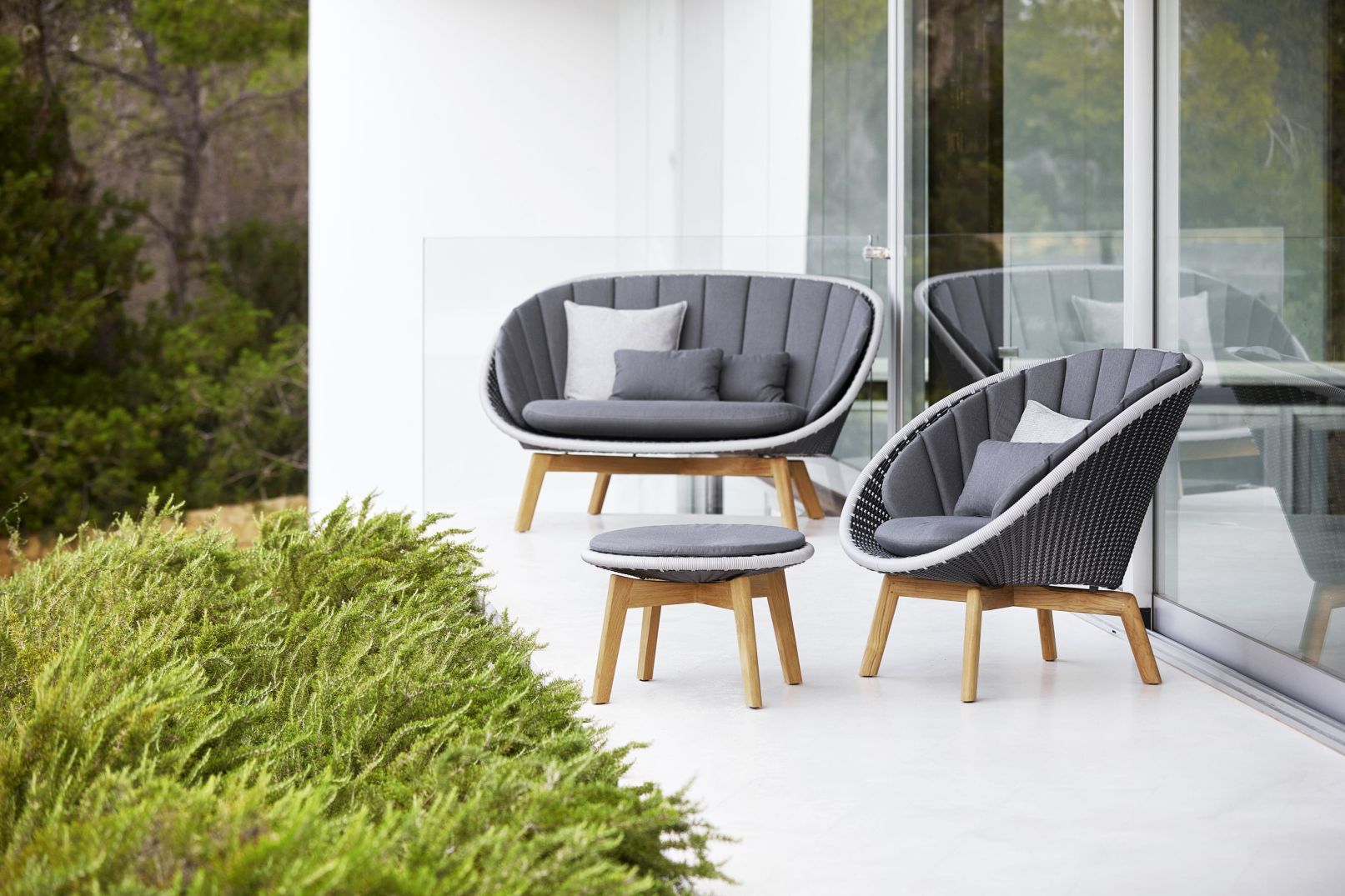 Graue Outdoor-Loungegruppe mit Sofa, Sessel und Hocker aus Rattan und Holz für Terrasse und Garten.