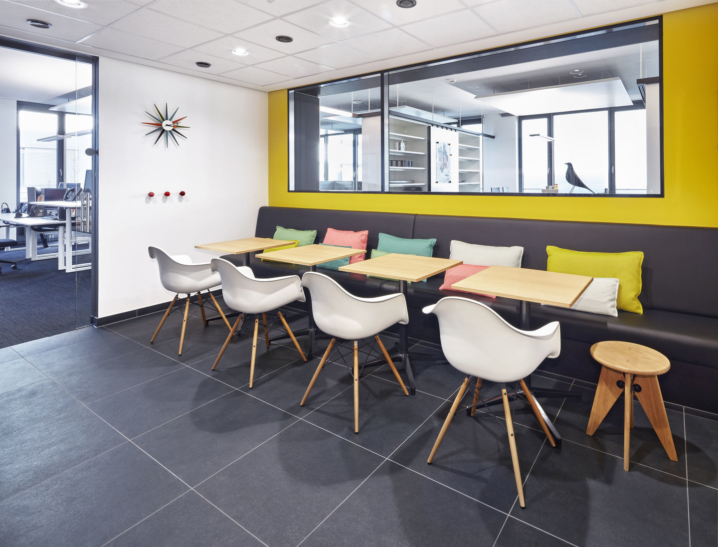 Büro-Szene mit weißen Eames Plastic Arm Chairs DAW von Vitra an kleinen Tischen.