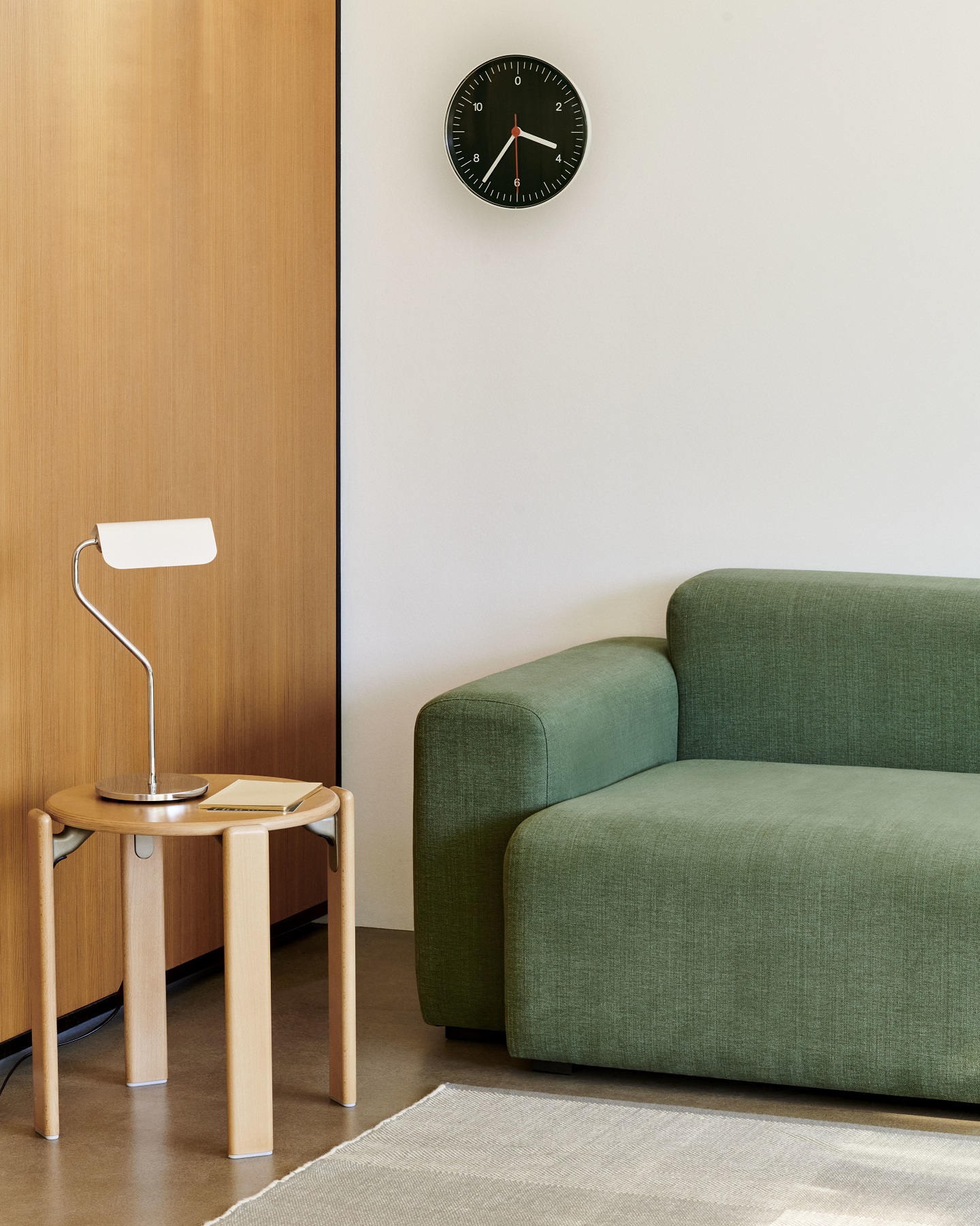 Nahaufnahme der Apex Table Lamp Oyster Tischleuchte von Hay auf einem Holztisch neben einem grünen Sofa.