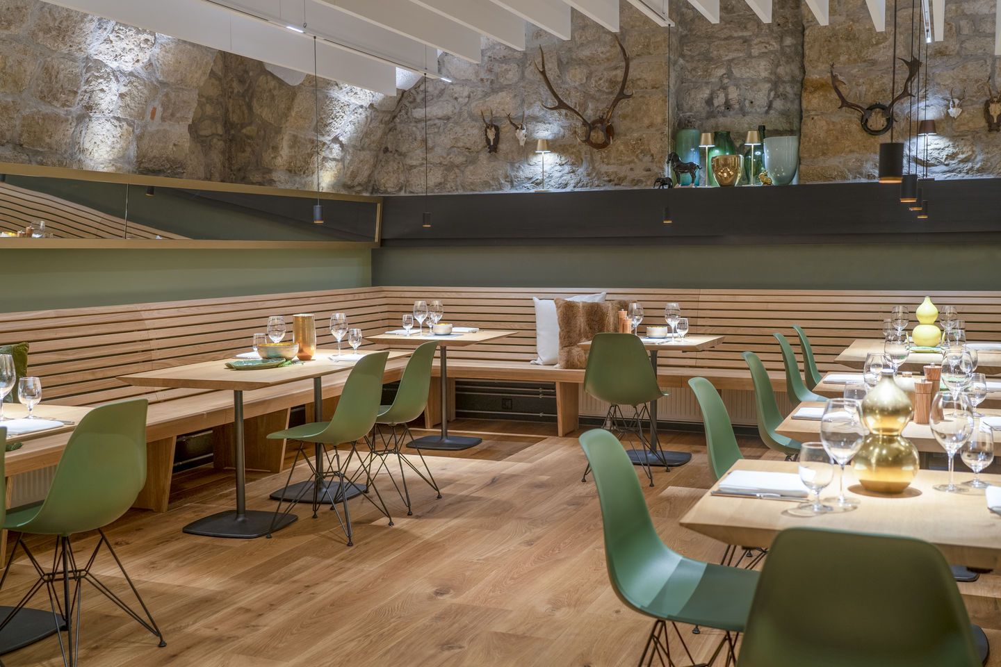 Innenaufnahme eines Restaurants mit Tischen und grünen Eames DSR Stühlen mit Sitzpolster von Vitra.