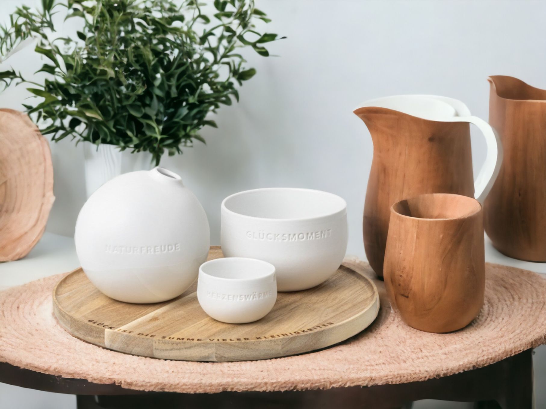 Produktfoto: Keramik-Vasen und Holz-Krüge auf Holztablett mit den Worten "Naturfreude", "Glücksmoment" und "Kerzenwärme".