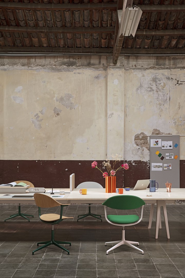 Mynt Bürodrehstühle von Vitra an einem langen Tisch in einem modernen Büro mit Blumen und Laptop.