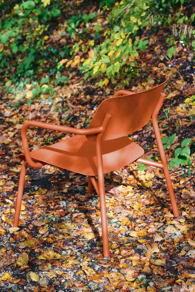 Nahaufnahme des orangefarbenen Fermob Studie Lounge Sessels Outdoor auf herbstlichem Laub.