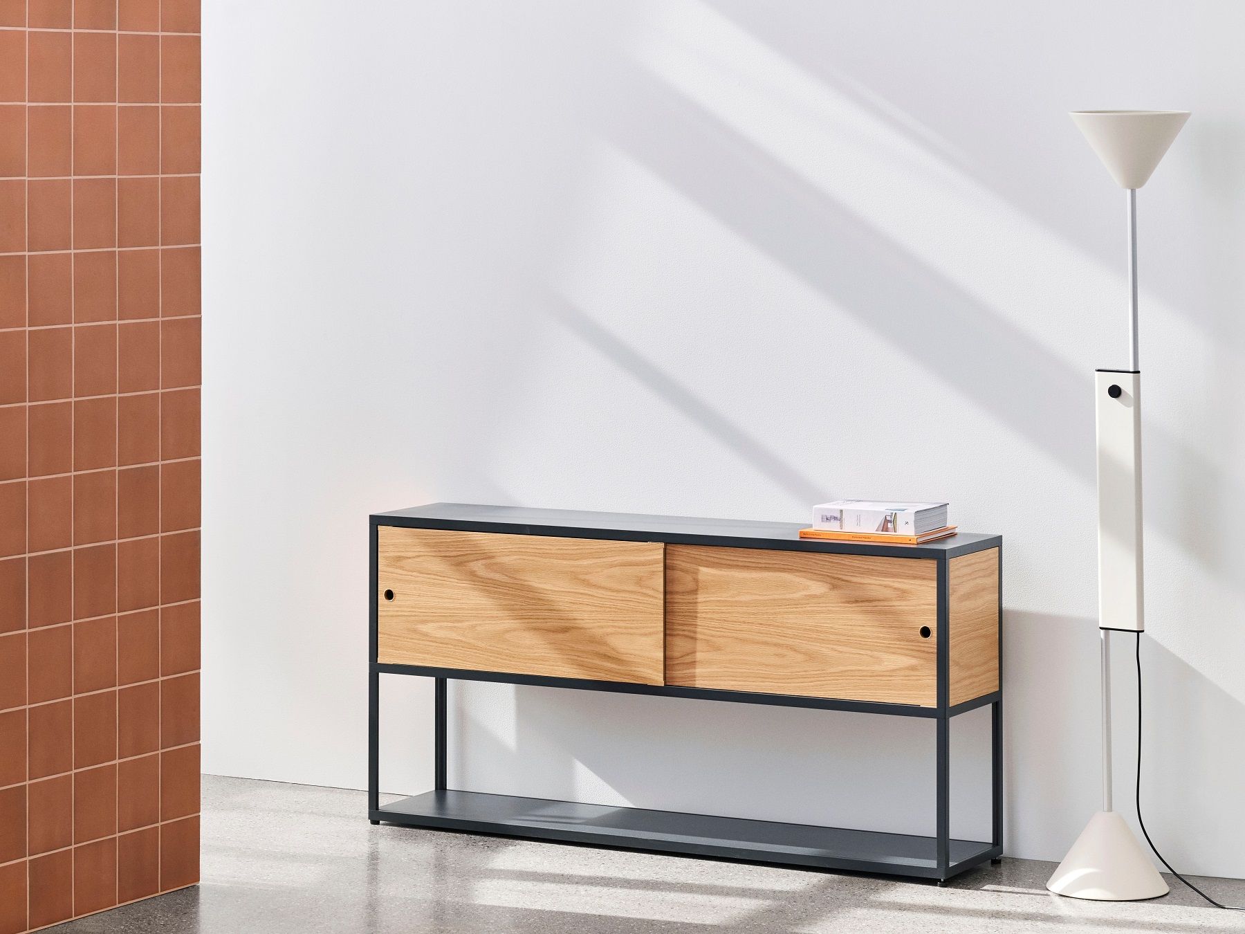Hay Twist Floor Lamp Stehleuchte in Weiß neben einem Sideboard mit Holzschiebetüren.