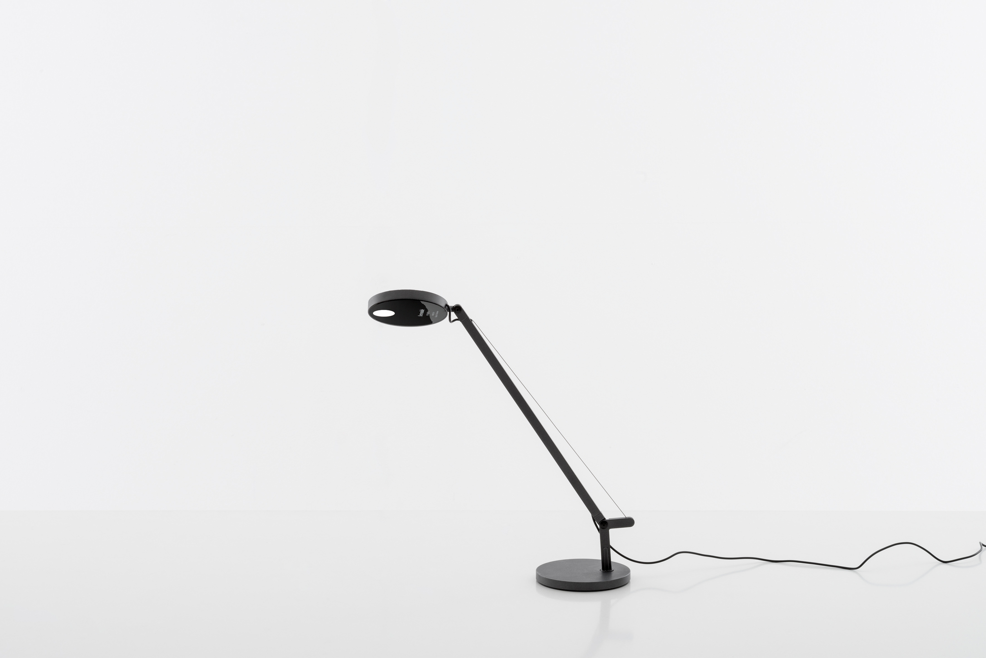 Schwarze Demetra Micro Tischleuchte von Artemide mit rundem Lampenkopf und verstellbarem Arm.