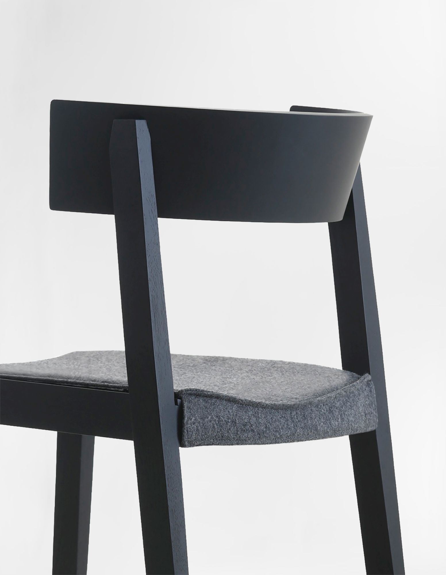 Detailaufnahme des Bik Stuhls von Prostoria: Schwarzes Holzgestell mit grauem, gepolstertem Sitzkissen, ideal für Esszimmer und Wohnbereich.