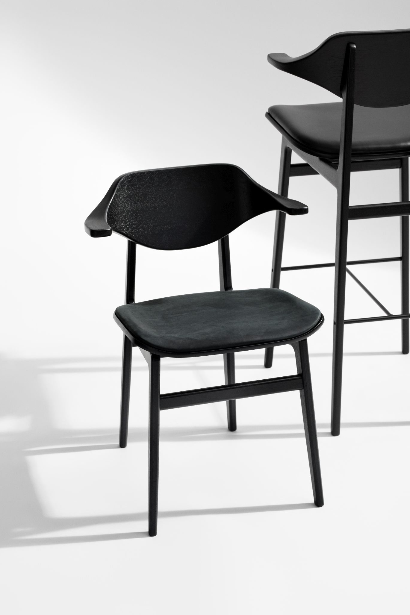Schwarzer Bufala Dining Chair Stuhl von NORR11 mit Armlehnen und Lederbezug vor hellem Hintergrund.