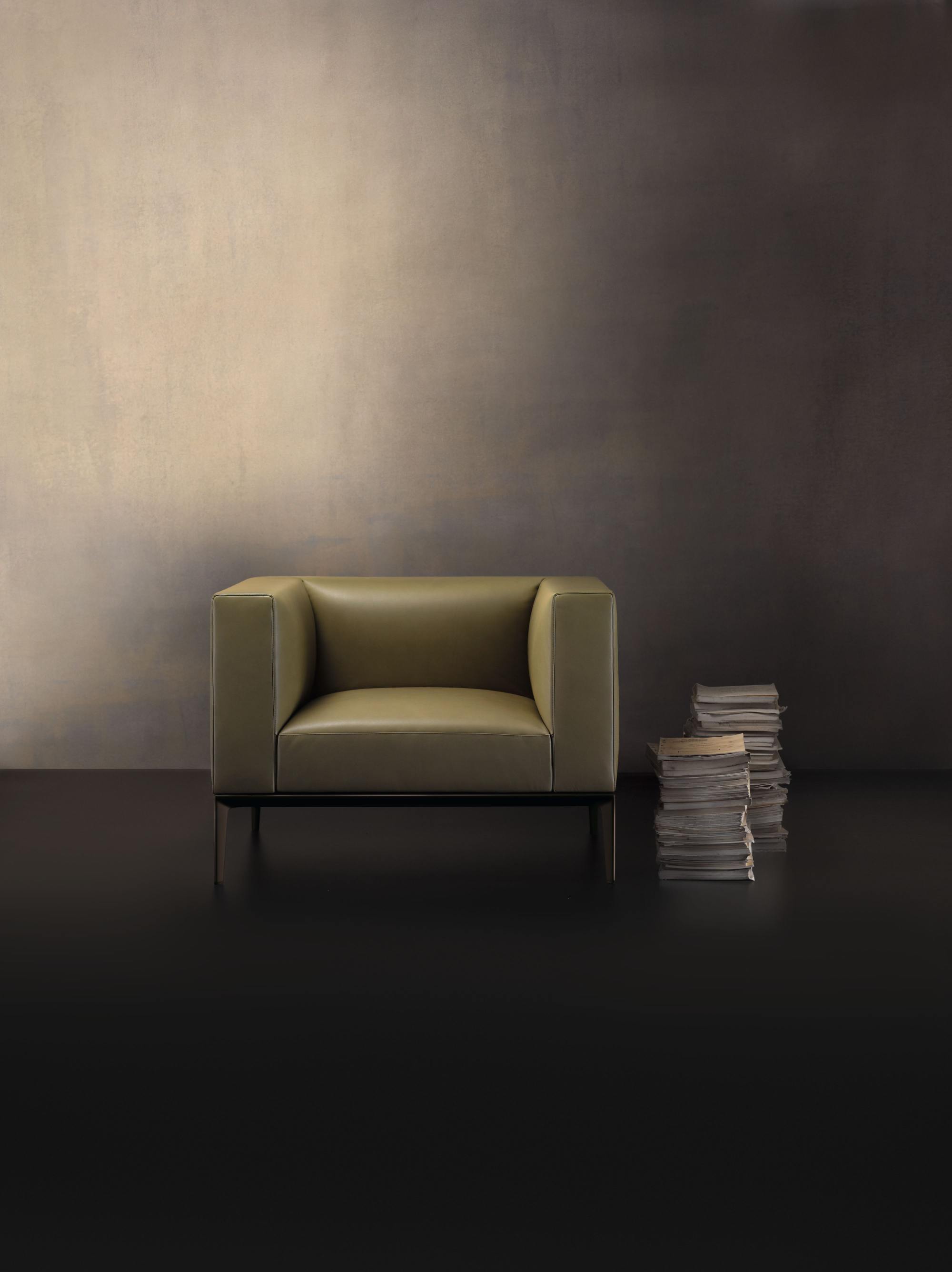 781 Jaan Sessel von Walter Knoll in olivgrünem Leder mit minimalistischem Design und Bücherstapel.