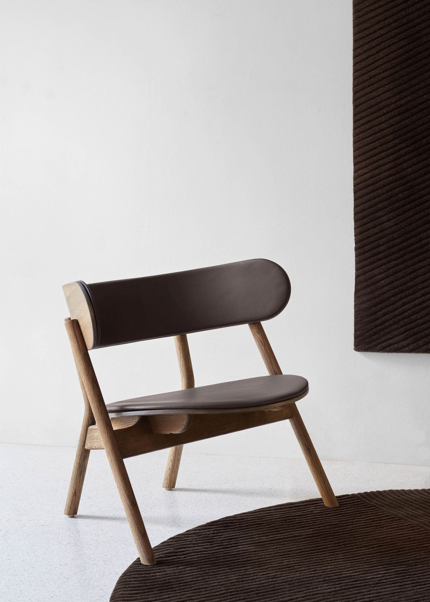 Oaki Lounge Chair mit brauner Polsterung. Moderner Sessel aus Holz und Leder.