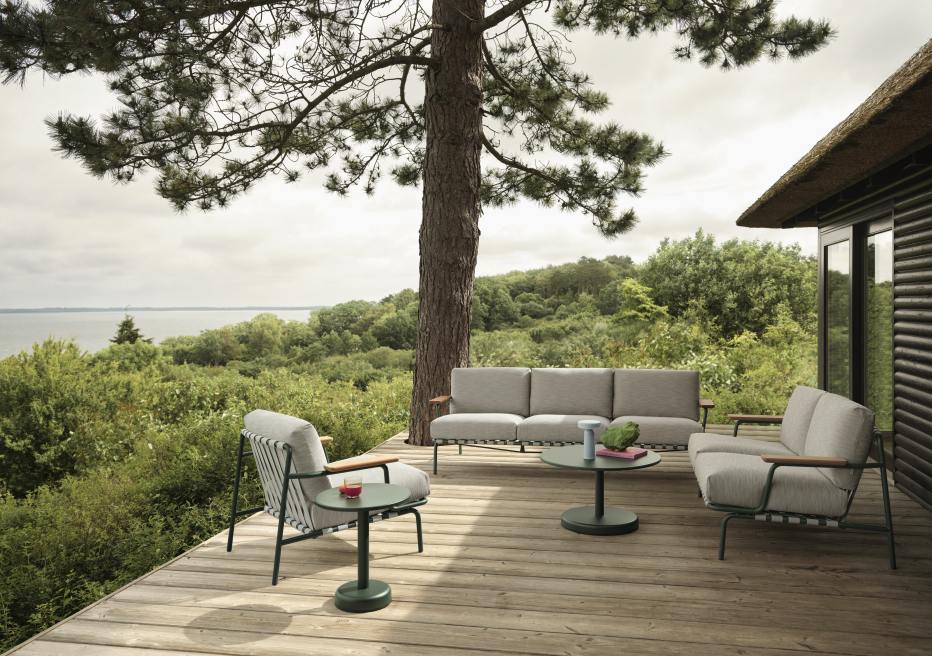 Muuto Settle Outdoor Sofa: Graues 2-Sitzer Sofa und Sessel auf Holzterrasse mit Meerblick. Gartenmöbel für Entspannung.
