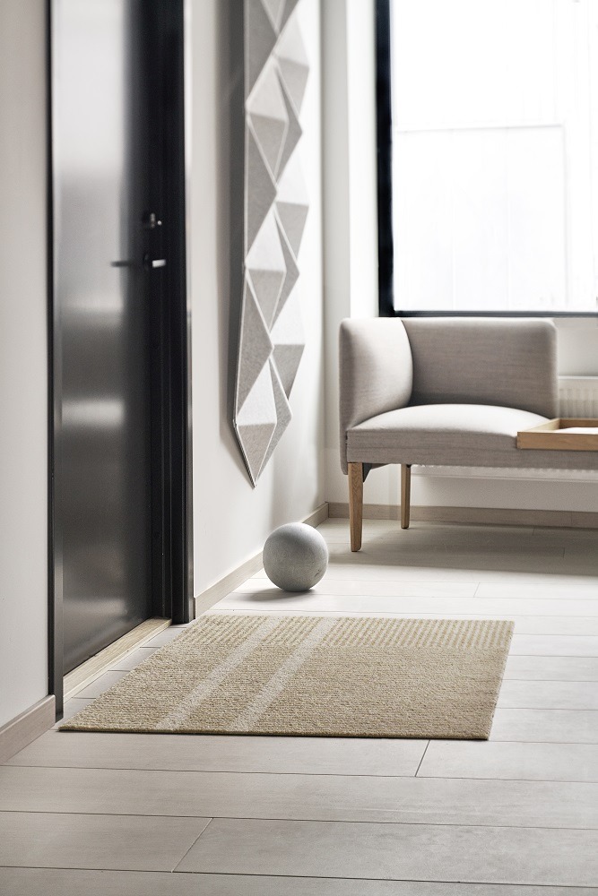 Beige Fußmatte "Løype" von Heymat im Eingangsbereich eines modernen Zuhauses, ideal für drinnen und draußen.